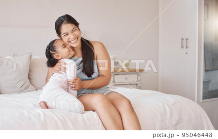 Mom on bed smile, hug happy girl in pajamas on morning in home on weekend or public holiday. Mother with child, express happiness and love in bedroom, while together on vacation or family travel 95046448