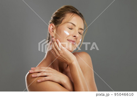 Skincare, beauty cream and woman with a face cream product against a grey mockup studio background. Happy and satisfied model with cosmetics for skin, body wellness and cosmetology or dermatology 95046610