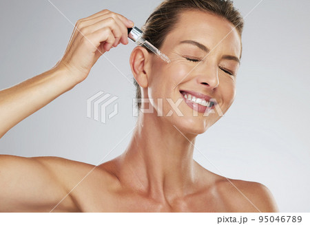 Face oil, skincare and mature woman with smile for dermatology product against a grey mockup studio background. Elderly model happy with natural facial liquid collagen serum for body wellness 95046789