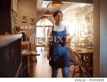 Woman, happy and waitress in restaurant working in apron with food menu in hand for table. Girl, smile and service work at luxury diner, cafe or coffee shop show happiness on face for job in London 95046889