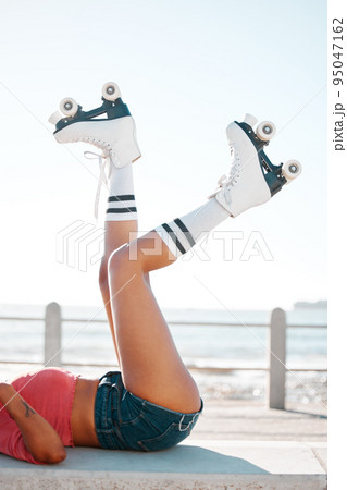 Fun, roller skates and beach vacation in summer with woman enjoying hobby, relax and freedom while skating. Legs and shoes of a female skater being fit and active while at sea for leisure and travel 95047162