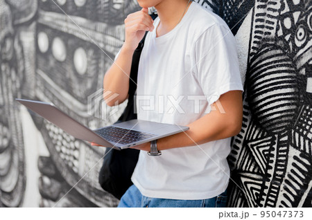 街中でパソコンを操作する男性 95047373