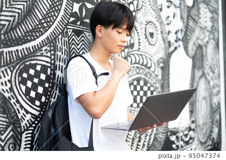 街中でパソコンを操作する男性 95047374