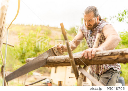 Man making an effort to cut a log Man making an effort to cut a log 95048706
