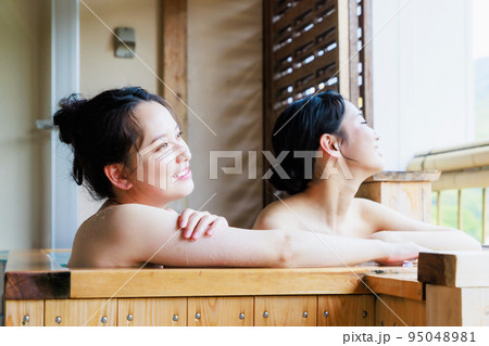 のんびり檜風呂に入る若い女性達 95048981