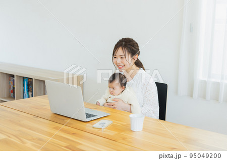 パソコンを見る赤ちゃんを抱っこしたママ 95049200