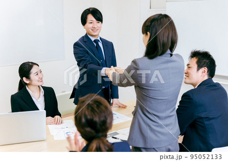商談で契約成立して握手するビジネスマンとビジネスウーマン 95052133
