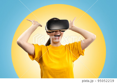 A young happy woman in virtual reality glasses, in amazement, stretches out her hands in different directions. Blue background with a yellow circle. The concept of virtual reality 95052219