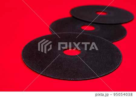 A cut-off wheel for a grinder tool on a red background with a place for copyspace text. Tools for construction and repair, workshop. A cut-off wheel for a grinder tool on a red background with a place for copyspace text. Tools for construction and repair, workshop. 95054038