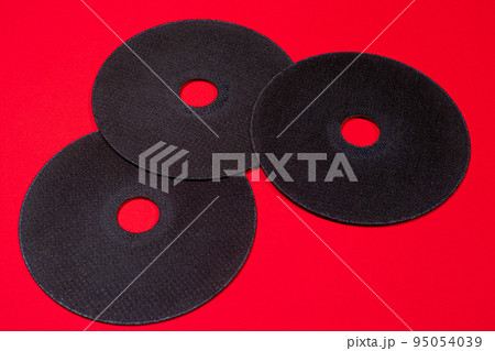 A cut-off wheel for a grinder tool on a red background with a place for copyspace text. Tools for construction and repair, workshop. A cut-off wheel for a grinder tool on a red background with a place for copyspace text. Tools for construction and repair, workshop. 95054039