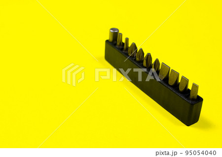 A set of screwdriver nozzles for a screwdriver on a yellow background with space for copyspace text. Tools for construction and repair shop 95054040