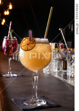 Orange alcoholic cocktail in a glass on the bar on a black background Orange alcoholic cocktail in a glass on the bar on a black background 95054680