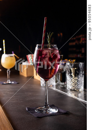 Two alcoholic cocktails pink and yellow on a dark bar. Two alcoholic cocktails pink and yellow on a dark bar. 95054683