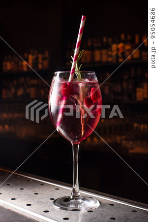 Raspberry cocktail with ice and a tube in a glass on a black background on the bar. Bright colorful berry cocktail with alcohol Raspberry cocktail with ice and a tube in a glass on a black background on the bar. Bright colorful berry cocktail with alcohol 95054686