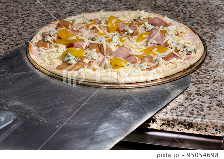 Pizza on a shovel will be fried in the oven. The process of making Italian pizza in a restaurant. Pizza on a shovel will be fried in the oven. The process of making Italian pizza in a restaurant. 95054698