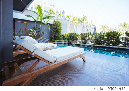 Beautiful luxury umbrella and chair around outdoor swimming pool in hotel and resort with coconut palm tree on blue sky  95054932