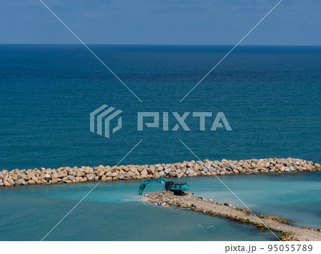 The excavator moves stones into the sea. Construction of breakwaters to protect the beach in Netanya in Israel. The excavator moves stones into the sea. Construction of breakwaters to protect the beach in Netanya in Israel. 95055789