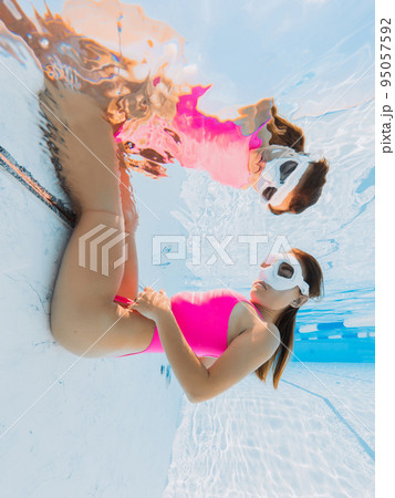 Freediver woman in swimwear with diving mask underwater in swimming pool. Freediver woman in swimwear with diving mask underwater in swimming pool. 95057592