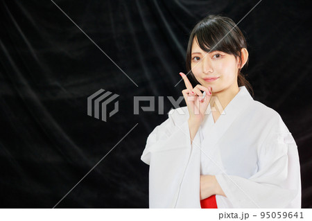 黒背景の余白を指さす巫女服の日本人女性 黒背景の余白を指さす巫女服の日本人女性 95059641