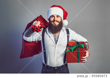 bearded smiling man in Santa's hat in white shirt holds sack and gift box. New Year concept  95060973