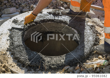 There is a utility worker who is constructing a pit for a septic tank the sewerage manhole, and reconstructing the sewage system 95061082
