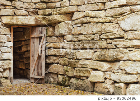 Open ancient wooden door in stone wall 95062496
