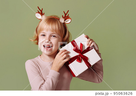 Girl with a Christmas present on a green background. 95063626
