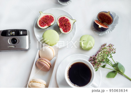aesthetic film camera flatlay, cups of coffee, figs and macarons on a white background, top view 95063634