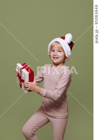Girl with a Christmas present on a green background. Girl with a Christmas present on a green background. 95063649