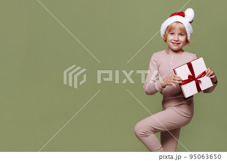 Girl with a Christmas present on a green background. Girl with a Christmas present on a green background. 95063650