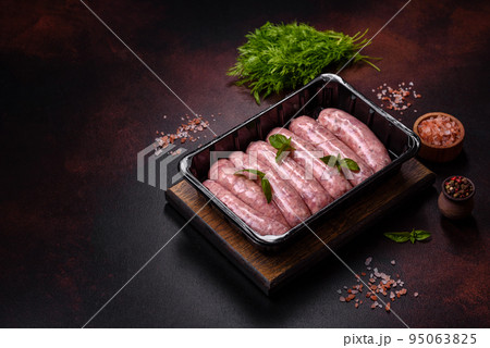 Raw sausages with ingredients on a cutting board on a dark concrete background with copy space 95063825