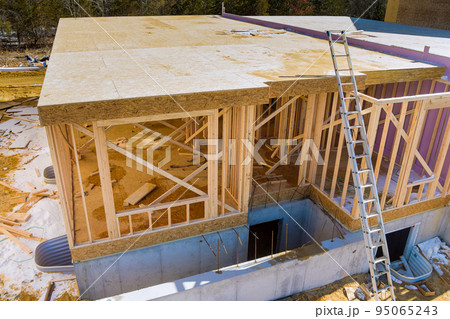 An under construction beam framing structure of a home on the construction site of a new residential home An under construction beam framing structure of a home on the construction site of a new residential home 95065243