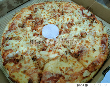 Close-up photo of the pizza slice still in the box. Pizza is made with a variety of toppings as a flavor variation with cheese as the base of the topping ingredients. 95065928