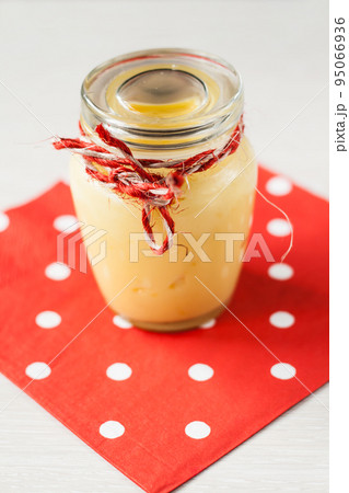 Lemon cream in a glass jar stands on a napkin Lemon cream in a glass jar stands on a napkin 95066936