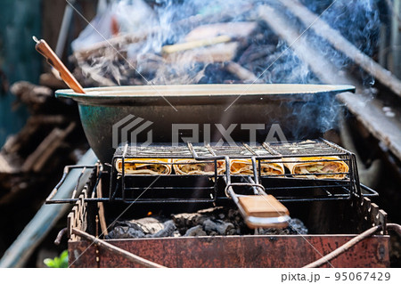 on the grill stands a cauldron in which to prepare meat and vegetables 95067429