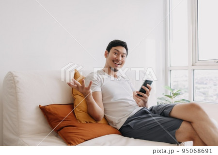 Happy man use smartphone in the living room for advertising content. Happy man use smartphone in the living room for advertising content. 95068691