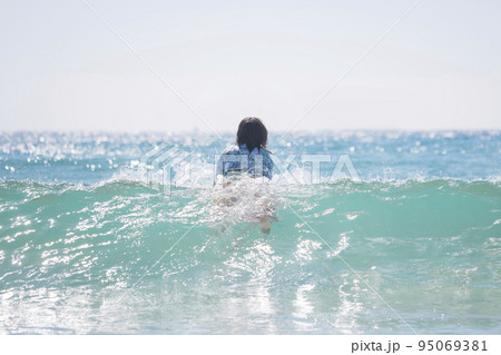 パドリングで沖に向かう若い女性　サーフ女子　サーフィン女子 95069381