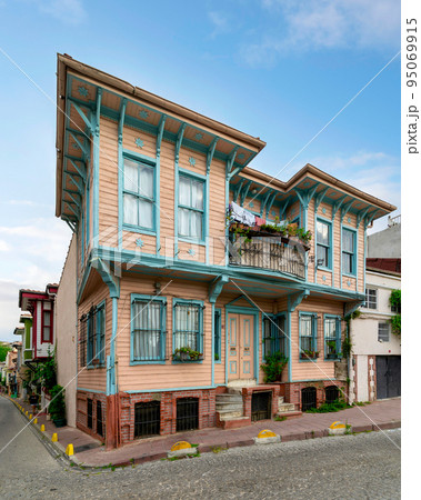 Old colorful wooden residential building with door, wrought iron windows, balcony, and climber plants, Istanbul, Turkey 95069915