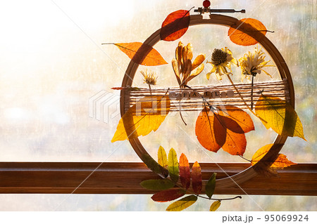 DIY door wreath from autumn colourful leaves and flowers. Fall home decor. 95069924