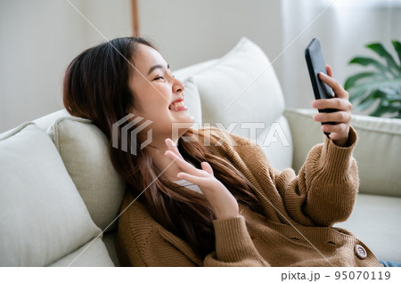 Happy young asian woman relaxing at home 95070119