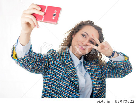 of a cute lovely woman taking selfie and showing peace sign with fingers over white background 95070622