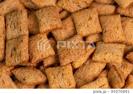 Crispy chocolate pads background macro. Cocoa cereal dessert for a fast breakfast. Morning breakfast dry chocolate pads close up. Chocolate flakes cereal pads with cream filling 95070891