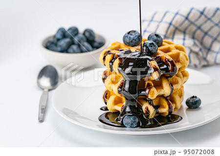 Pouring chocolate syrup on stack of fresh delicious homemade waffles. 95072008
