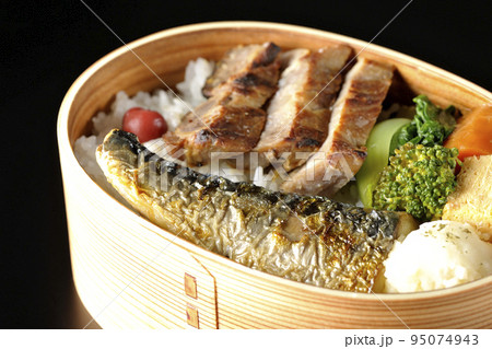 豚肉やポテサラ、玉子焼き等が曲げわっぱに入っている焼き魚弁当を黒背景で撮影 95074943