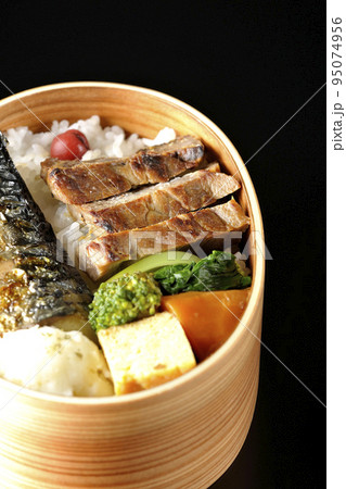 豚肉やポテサラ、玉子焼き等が曲げわっぱに入っている焼き魚弁当を黒背景で撮影 豚肉やポテサラ、玉子焼き等が曲げわっぱに入っている焼き魚弁当を黒背景で撮影 95074956