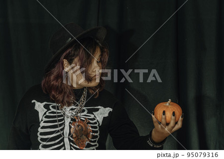 Young Asian woman in costume witch and hold pumpkin and book on black cloth background of Halloween. Portrait of teen dressed up as witch for celebrate Halloween. Young Asian woman in costume witch and hold pumpkin and book on black cloth background of Halloween. Portrait of teen dressed up as witch for celebrate Halloween. 95079316