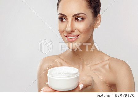 Young Woman Holding Cosmetic Moisturizing Cream. Soft Skin And Naked Shoulders, Model With Light Nude Make-Up, Portrait Of Girl Face With Clean Healthy Skin. Young Woman Holding Cosmetic Moisturizing Cream. Soft Skin And Naked Shoulders, Model With Light Nude Make-Up, Portrait Of Girl Face With Clean Healthy Skin. 95079370