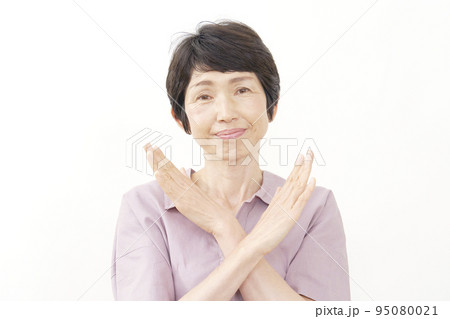 腕でばつ印するシニア女性　白背景 95080021