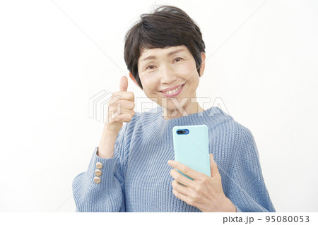 スマホを持ってグッドサインするシニア女性　白背景 95080053