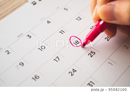 Female Hand with pen mark on calendar date Female Hand with pen mark on calendar date 95082100